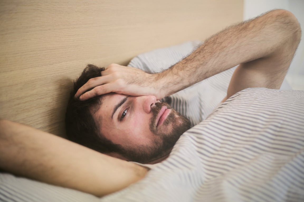 Pensive man lying in bed in morning